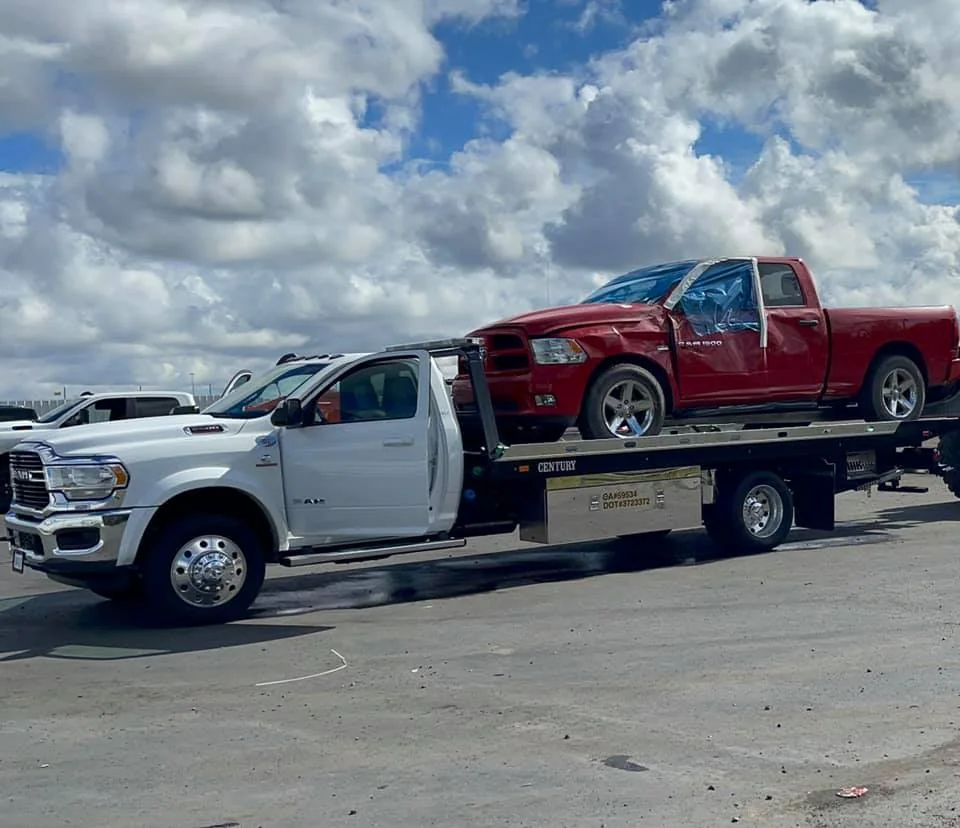 Red pickup carried by a white Tiger Towing truck